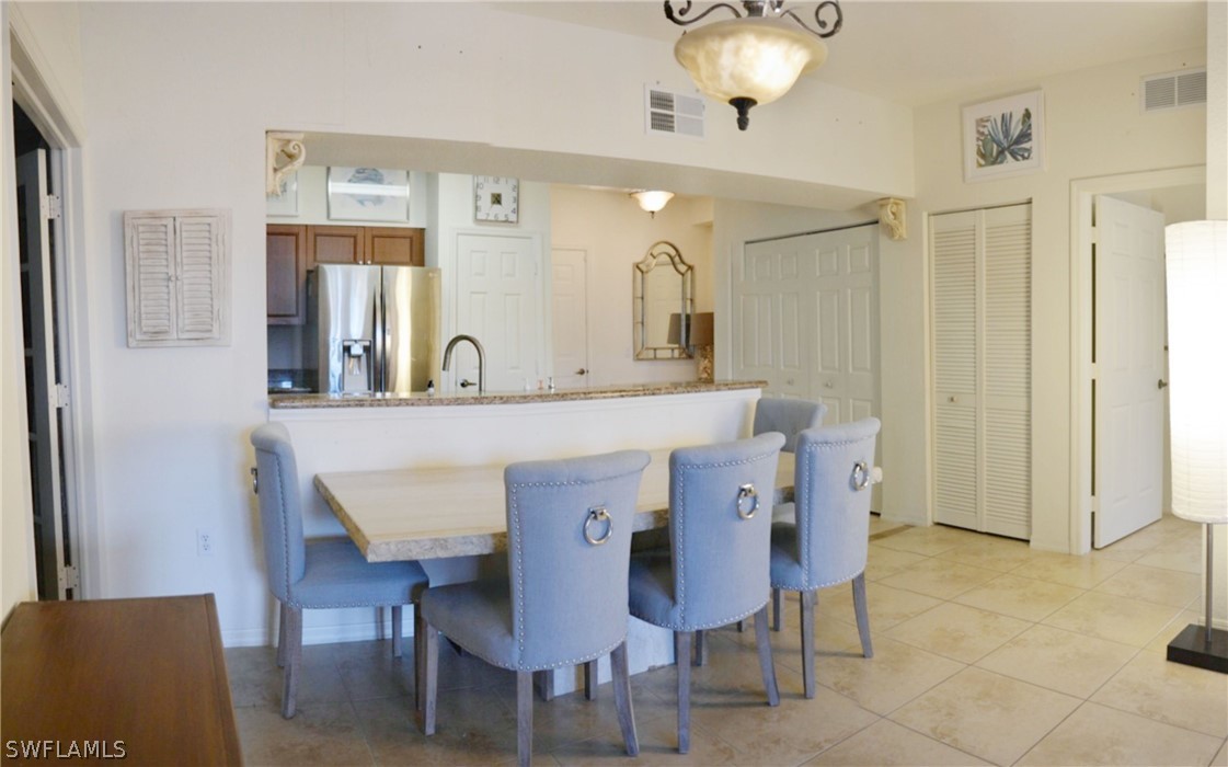 20121 Estero Gardens Circle, Unit 101 Estero, FL 33928 - Photo 11 of 24 a kitchen with a dining table chairs and white cabinets
