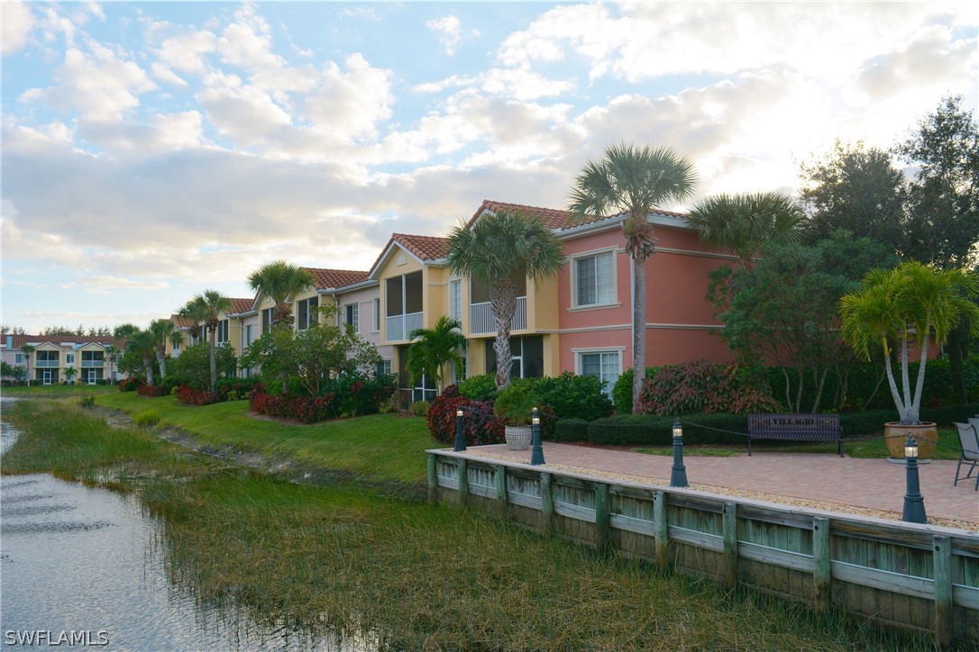 20121 Estero Gardens Circle, Unit 101 Estero, FL 33928 - Photo 22 of 24 a view of a white house next to a yard with big trees