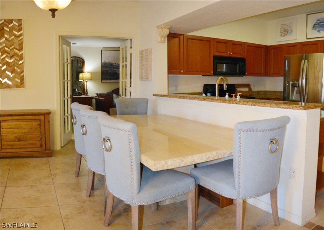 20121 Estero Gardens Circle, Unit 101 Estero, FL 33928 - Photo 10 of 24 a living room with stainless steel appliances a table chairs and a refrigerator