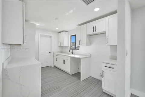 a kitchen with white cabinets appliances a sink and a counter top space