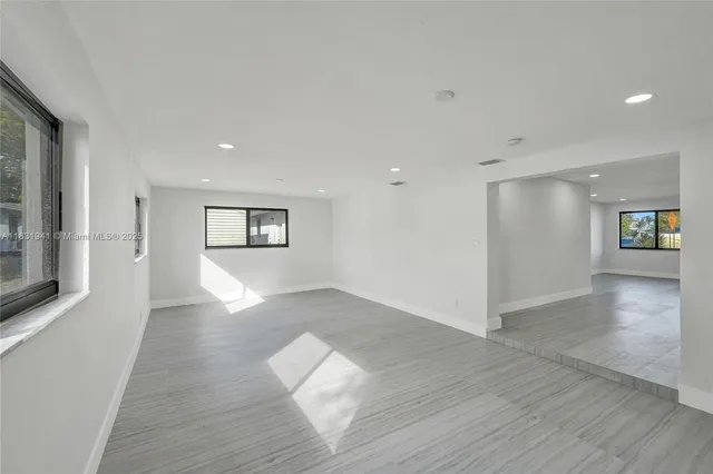 a view of empty room with wooden floor and a window