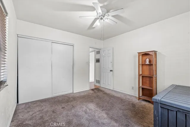 a view of an empty room with window and chandelier fan