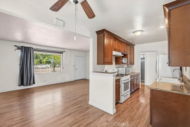 a kitchen with stainless steel appliances granite countertop a refrigerator a stove top oven a sink dishwasher and wooden floor