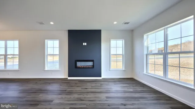 a view of an empty room with wooden floor and window