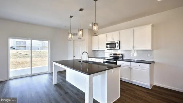 a kitchen with granite countertop a sink a counter space appliances and cabinets