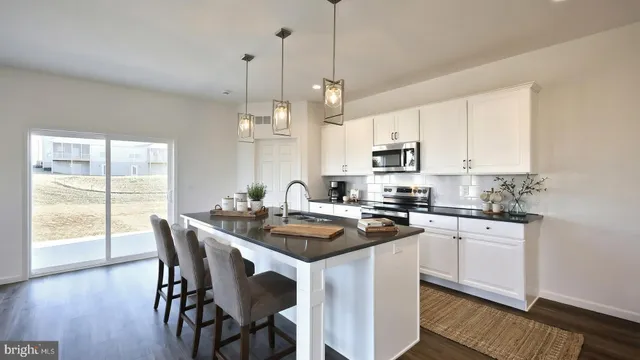 a kitchen with stainless steel appliances granite countertop a stove a sink a microwave a dining table and chairs with wooden floor