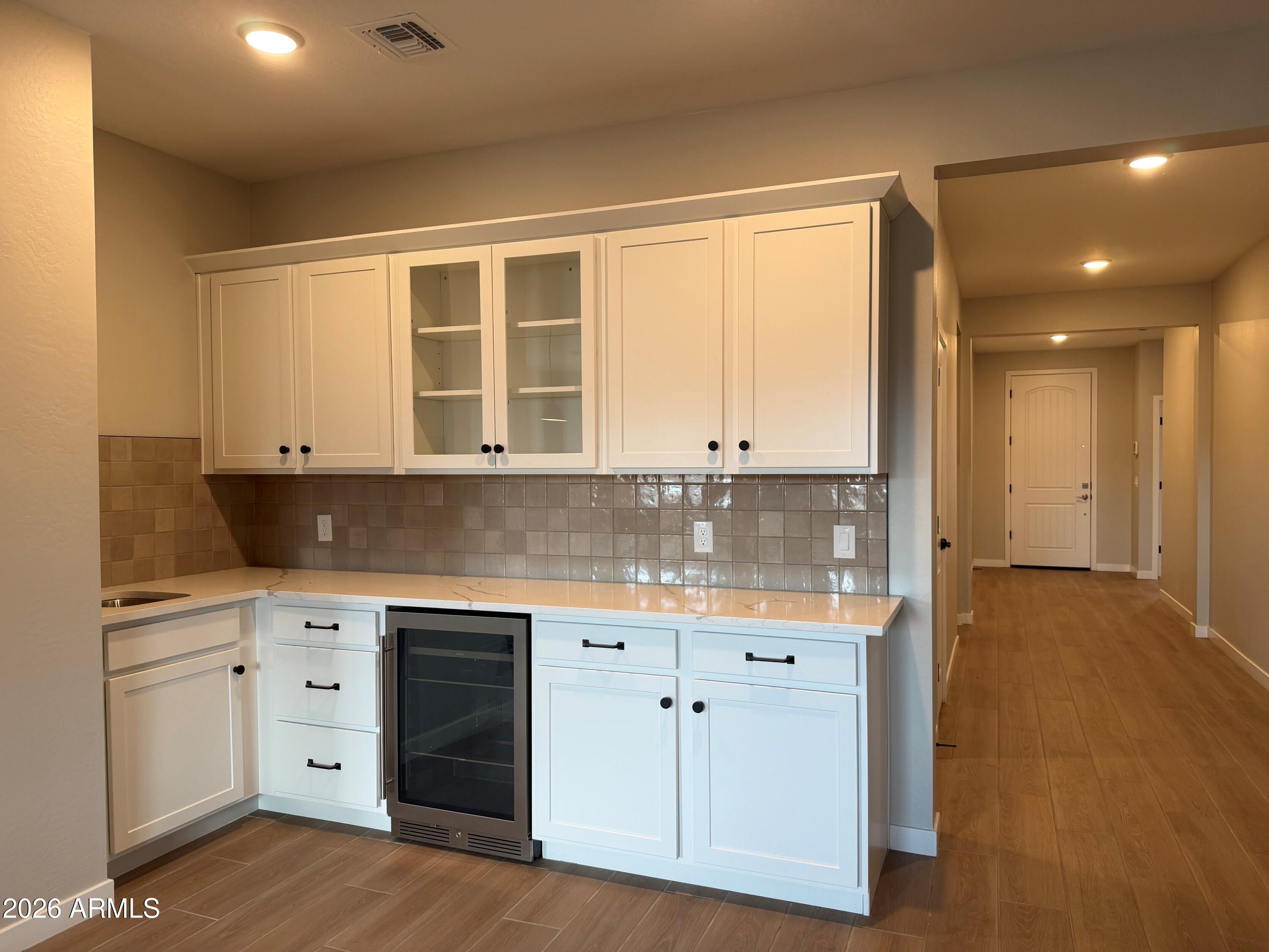 17547 West Fulton Street Goodyear, AZ 85338 - Photo 3 of 10 a kitchen with white cabinets and wooden floor