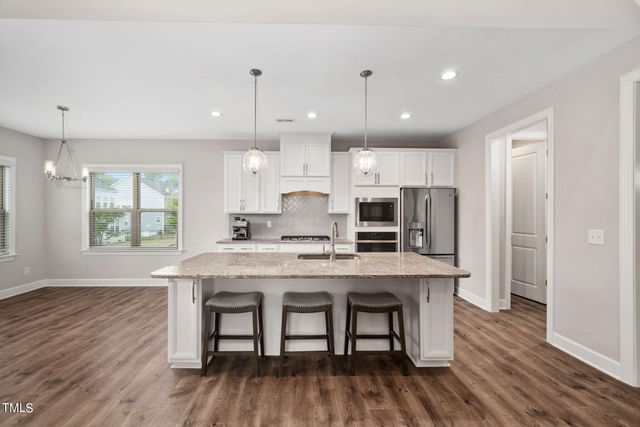 a kitchen with stainless steel appliances granite countertop a kitchen island hardwood floor sink and stove