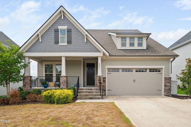 a front view of a house with a yard and potted plants
