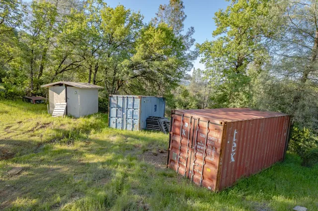 a view of a backyard with wooden fence and large trees