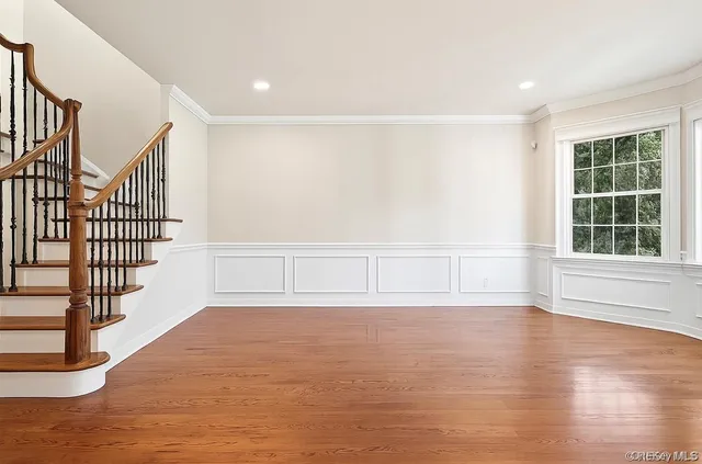 a view of an empty room with wooden floor and windows