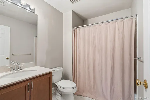 a bathroom with a granite countertop sink and a toilet