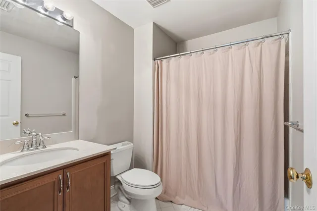 a bathroom with a granite countertop sink and a toilet