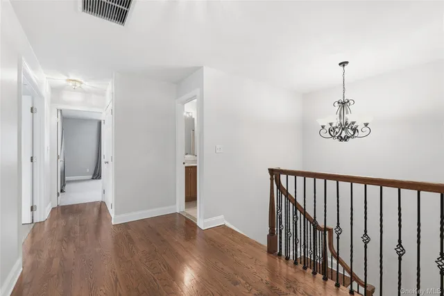 a view of a hallway with wooden floor and a chandelier