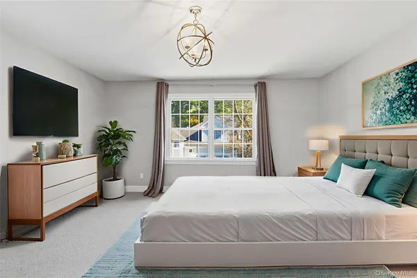 a bedroom with a large bed and a flat tv screen on dresser