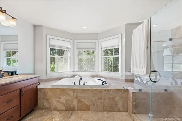 a bathroom with a granite countertop double vanity sink a mirror and a bathtub