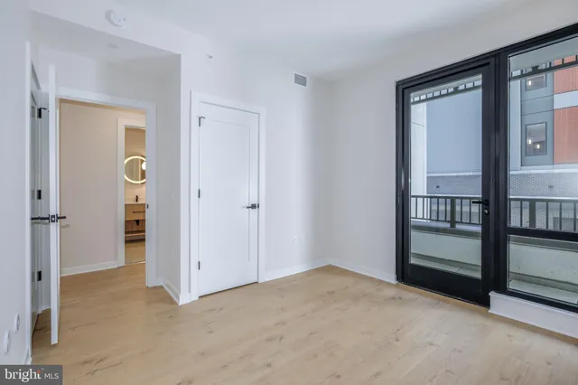 a view of an empty room with a window and wooden floor