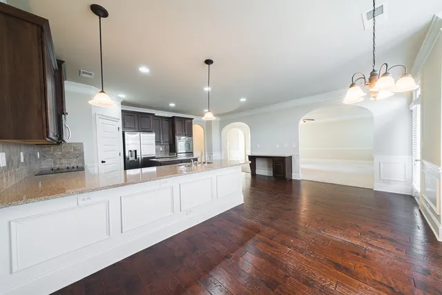 a large kitchen with granite countertop a stove a sink and a wooden floor