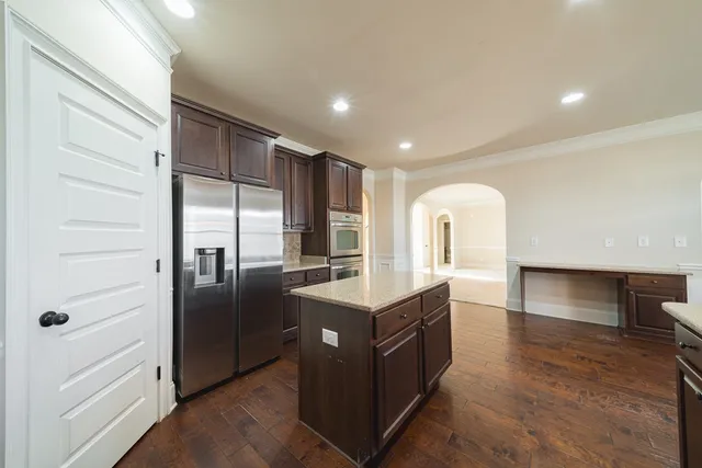 a kitchen with stainless steel appliances kitchen island granite countertop a refrigerator and a stove