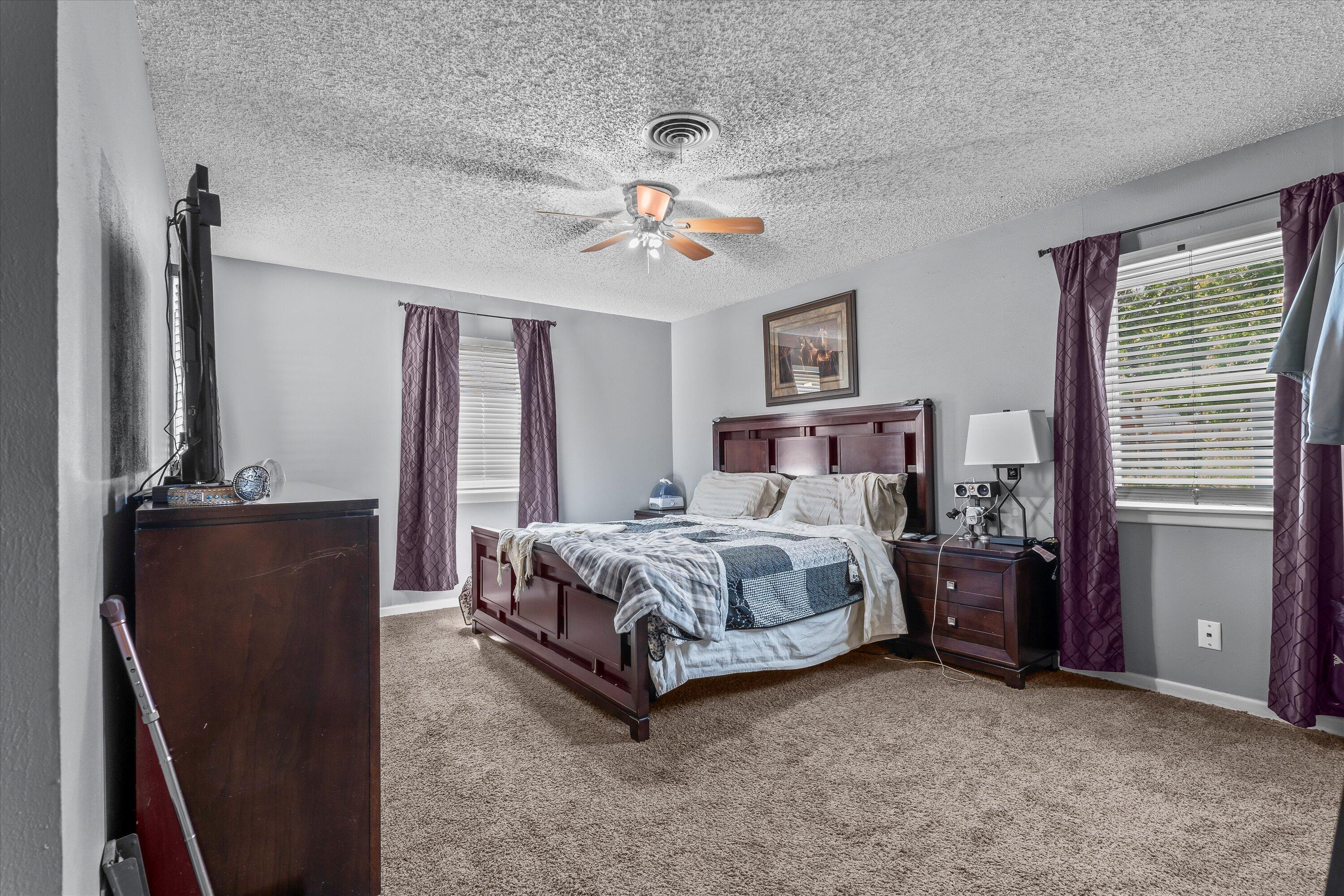 102 3rd Street Plains, TX 79355 - Photo 14 of 27 a spacious bedroom with a bed and a chandelier