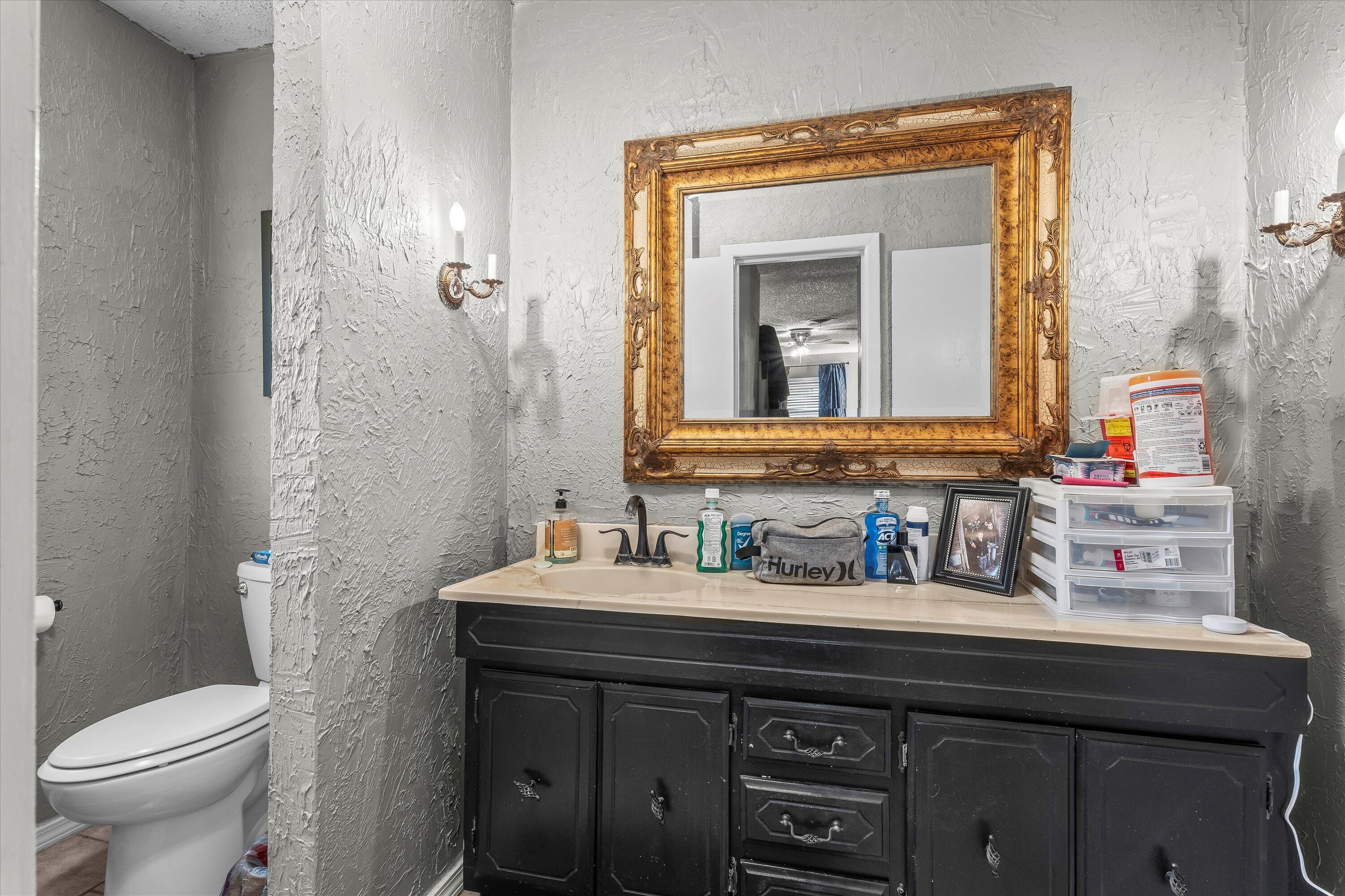 102 3rd Street Plains, TX 79355 - Photo 15 of 27 a bathroom with a toilet sink and mirror