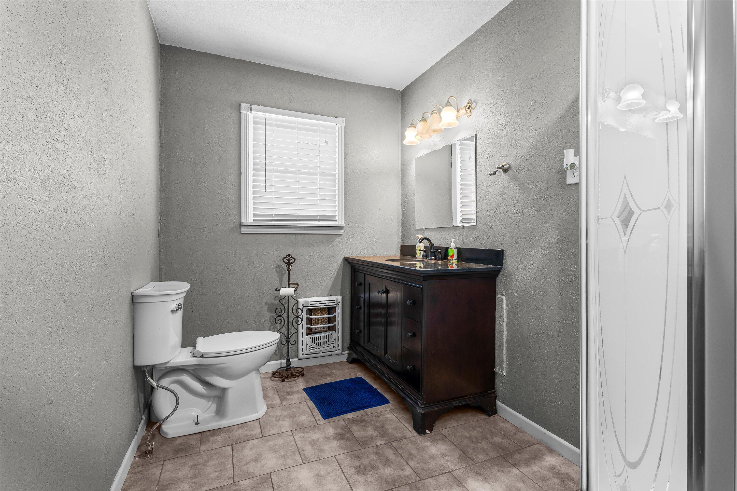 102 3rd Street Plains, TX 79355 - Photo 19 of 27 a bathroom with a toilet a sink and mirror