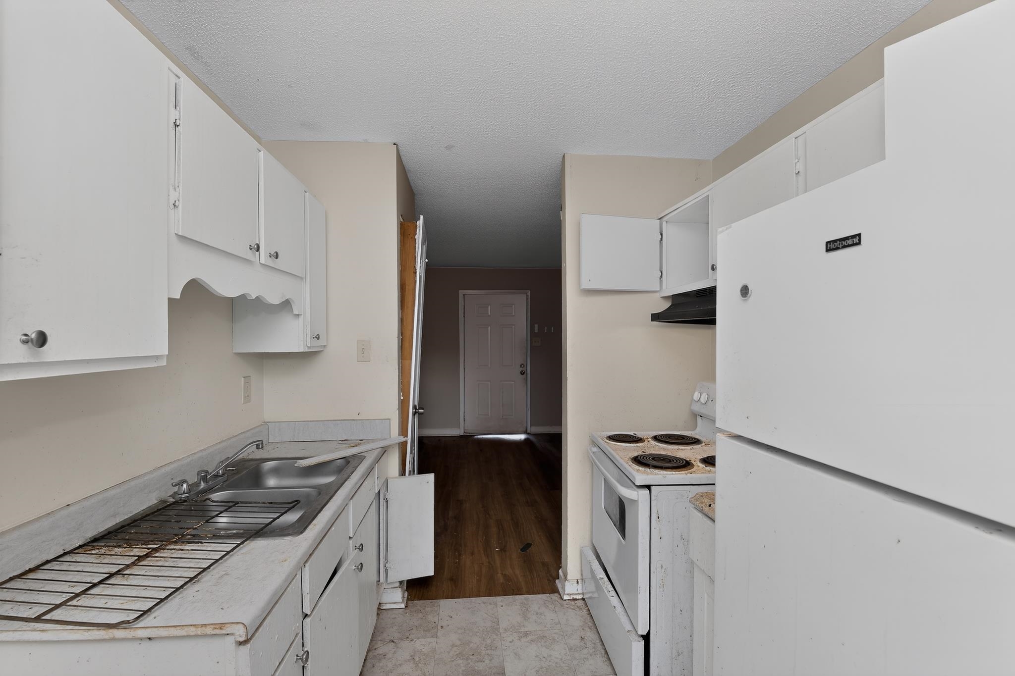 3953 McCain Road Memphis, TN 38109 - Photo 7 of 15 Compact kitchen featuring white cabinetry, a double basin stainless steel sink, a refrigerator, and an electric range
