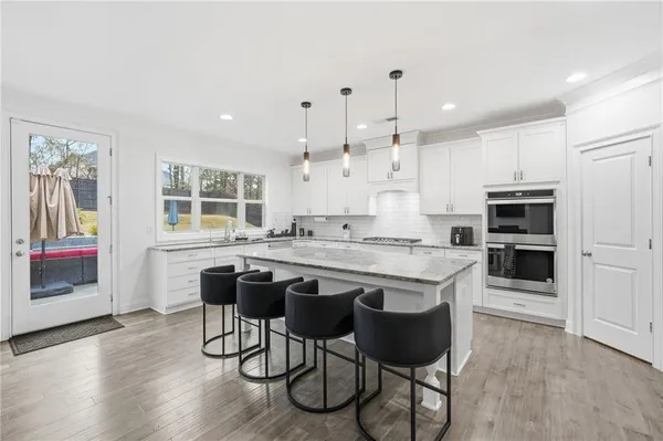 a kitchen with stainless steel appliances granite countertop a table chairs sink refrigerator and cabinets