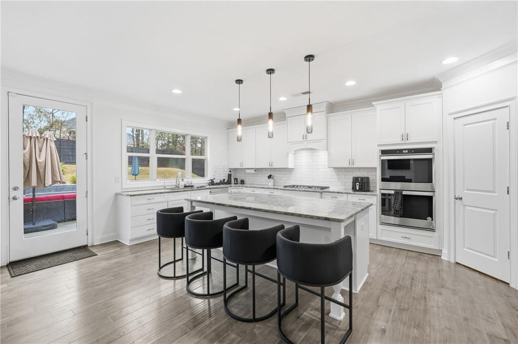 5115 Five Forks Trickum Road Southwest Lilburn, GA 30047 - Photo 15 of 63 a large kitchen with kitchen island a island a stove a table and chairs in it