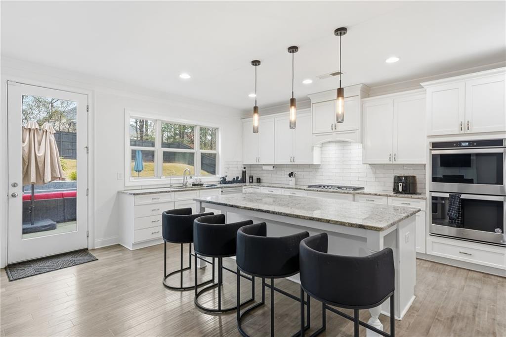 5115 Five Forks Trickum Road Southwest Lilburn, GA 30047 - Photo 16 of 63 a kitchen with stainless steel appliances granite countertop a stove a sink a microwave a dining table and chairs with wooden floor