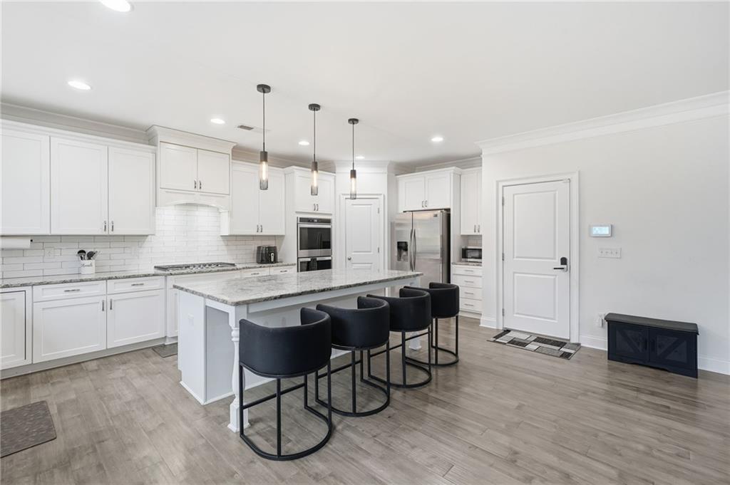 5115 Five Forks Trickum Road Southwest Lilburn, GA 30047 - Photo 18 of 63 a kitchen with stainless steel appliances kitchen island granite countertop a table chairs sink refrigerator and cabinets
