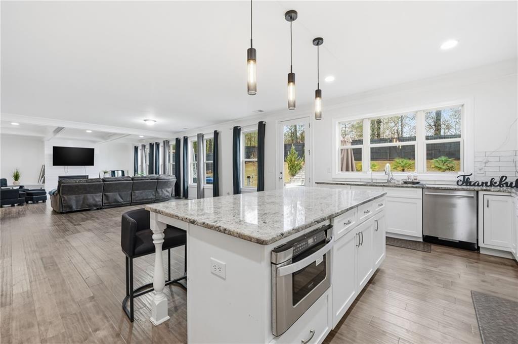 5115 Five Forks Trickum Road Southwest Lilburn, GA 30047 - Photo 22 of 63 a kitchen with stainless steel appliances granite countertop a stove and chairs