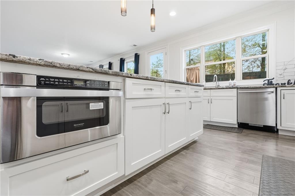 5115 Five Forks Trickum Road Southwest Lilburn, GA 30047 - Photo 23 of 63 a kitchen with stainless steel appliances granite countertop a stove and white cabinets