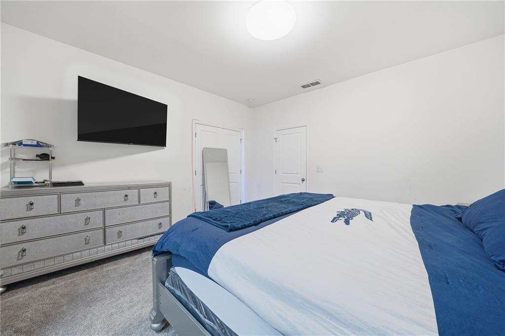 5115 Five Forks Trickum Road Southwest Lilburn, GA 30047 - Photo 37 of 63 a bedroom with a bed and a flat tv screen on dresser