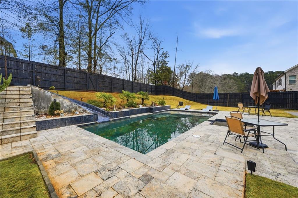 5115 Five Forks Trickum Road Southwest Lilburn, GA 30047 - Photo 52 of 63 a view of swimming pool with lounge chair and dinning table under an umbrella