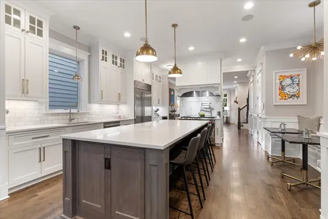 a open kitchen with stainless steel appliances granite countertop a stove a sink dishwasher a refrigerator and a dining table with wooden floor