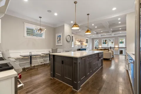 a large white kitchen with a large island oven a stove and a wooden floors