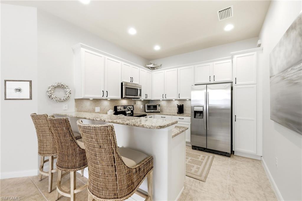 8658 Genova Court Naples, FL 34114 - Photo 9 of 49 Kitchen with Breakfast bar and stainless steel applicances