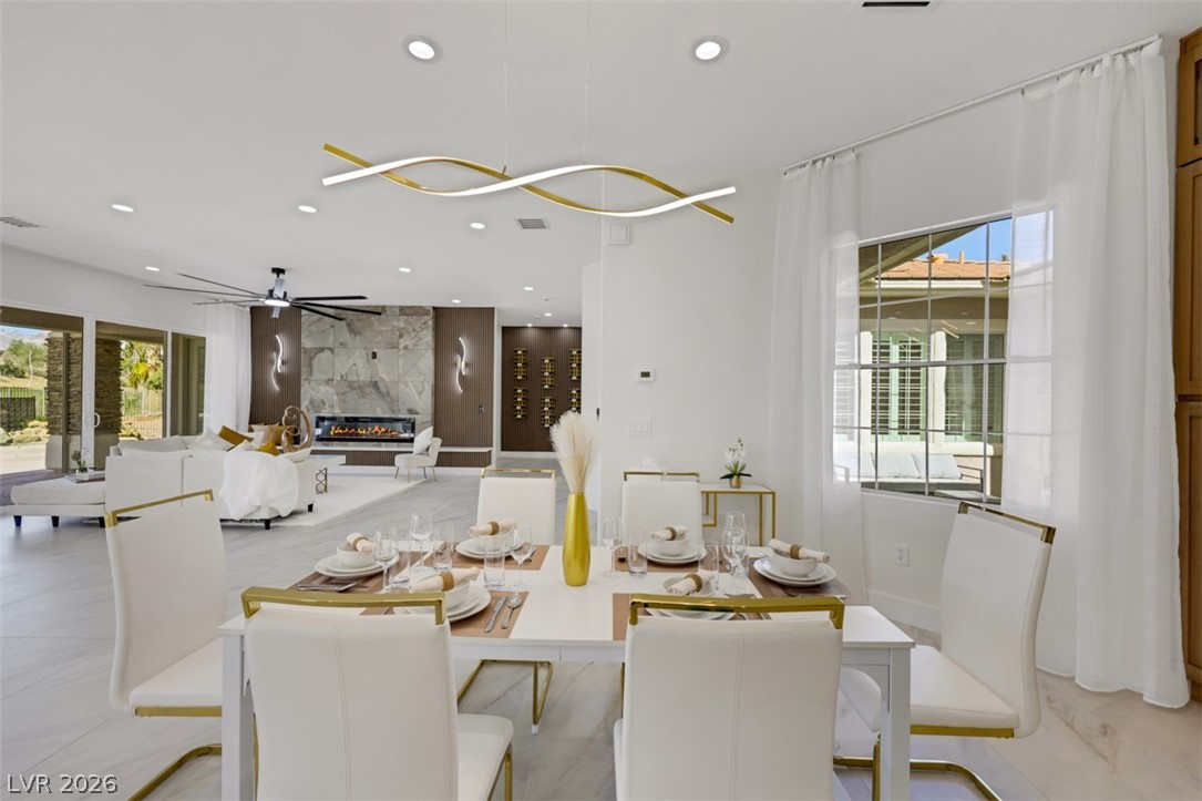 5015 Rivedro Street Las Vegas, NV 89135 - Photo 28 of 91 A striking modern dining room flows into an inviting living area with a sleek fireplace.