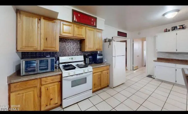 a living room with stainless steel appliances furniture a rug and a kitchen view