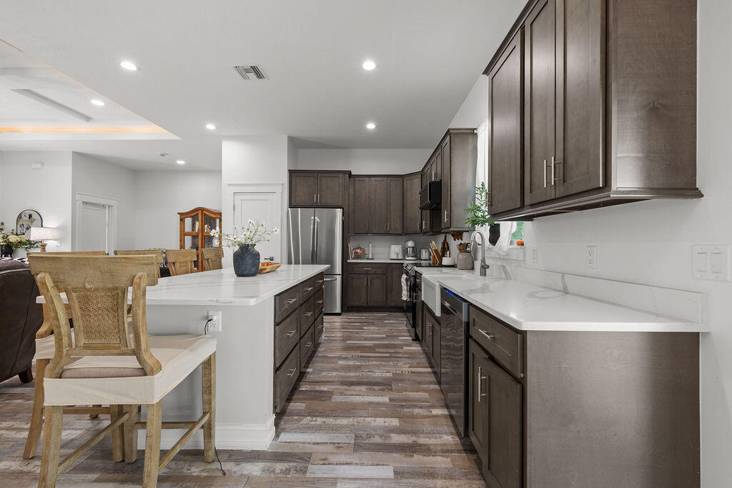 1014 Southwest 11th Street Okeechobee, FL 34974 - Photo 9 of 45 a kitchen with stainless steel appliances granite countertop a sink a stove top oven a refrigerator with island and chairs