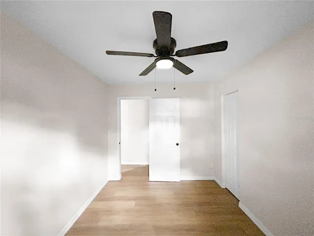 a view of a hallway with a chandelier fan and wooden floor