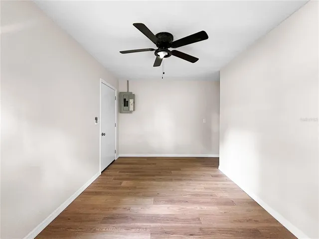an empty room with wooden floor and ceiling fan