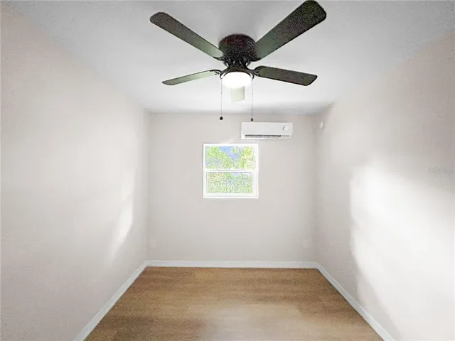 an empty room with a window and a ceiling fan