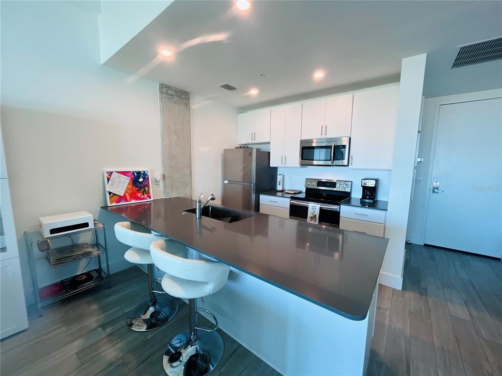 332 Cocoanut Avenue, Unit 507 Sarasota, FL 34236 - Photo 9 of 34 a kitchen with a dining table chairs sink and microwave