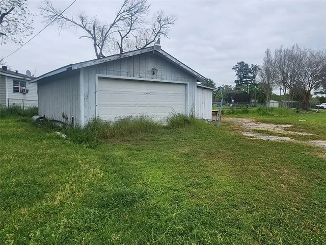a backyard of a house with plants and large tree