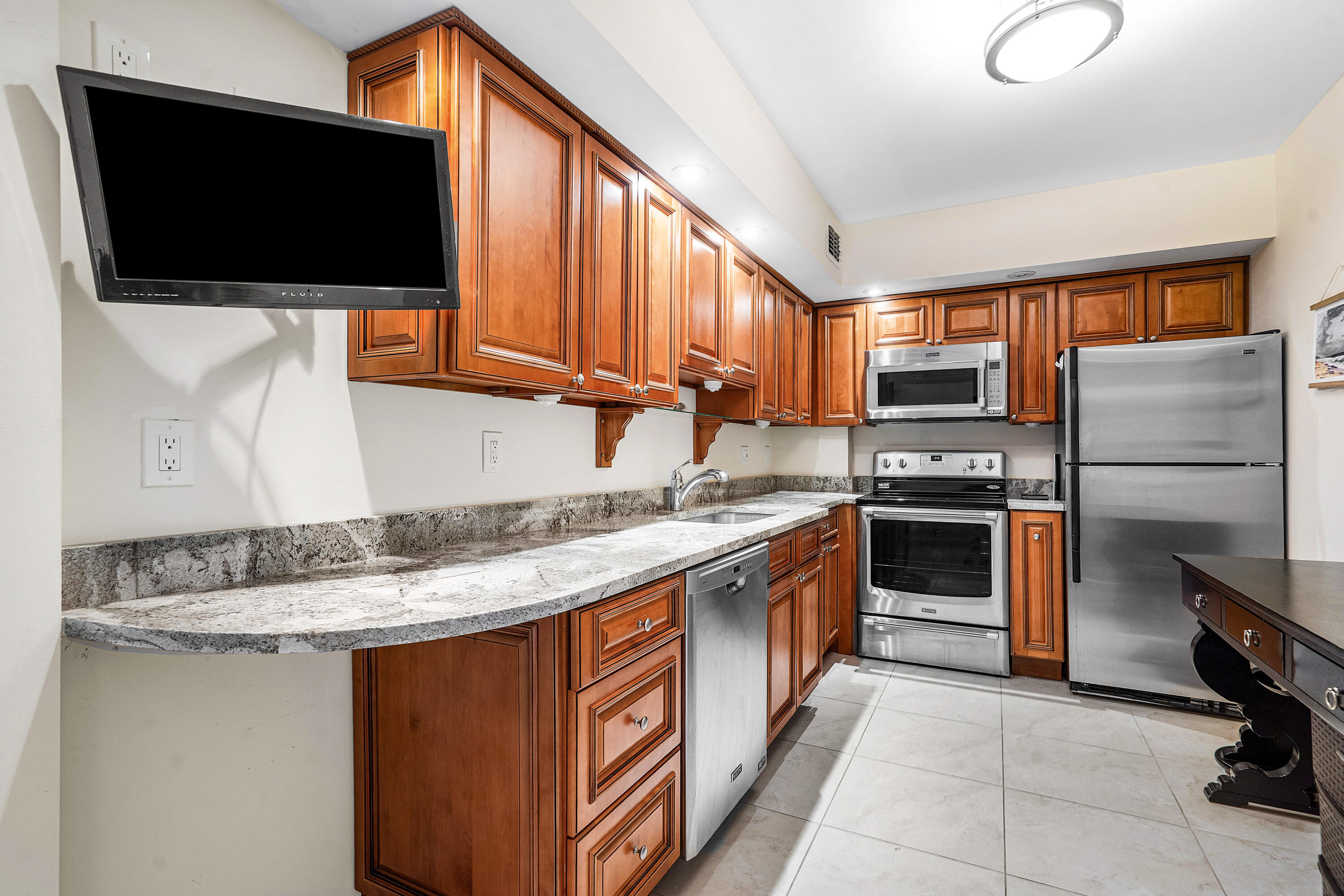 3450 South Ocean Boulevard, Unit 714 Palm Beach, FL 33480 - Photo 5 of 27 a kitchen with stainless steel appliances granite countertop a stove top oven a sink and a microwave