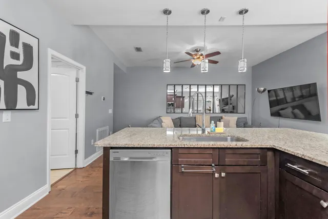 a kitchen with a granite countertop cabinets a sink dishwasher and a stove with wooden floor