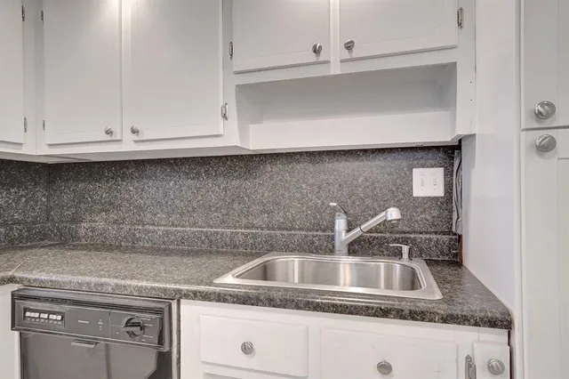 a kitchen with granite countertop white cabinets and a sink