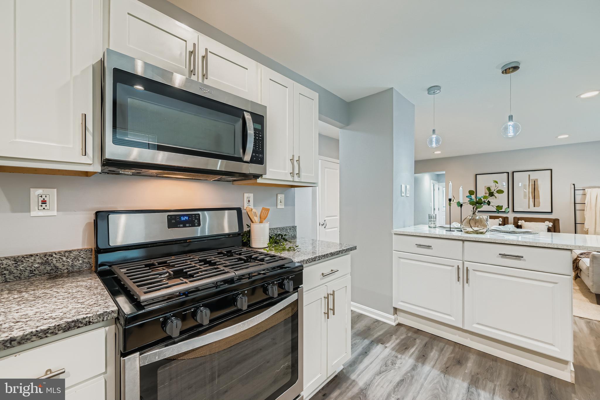 1229 North Point Road Dundalk, MD 21222 - Photo 5 of 28 a kitchen with stainless steel appliances a sink dishwasher stove and microwave with wooden floor